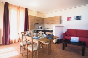 A modern living space with a dining area, kitchen, and a red sofa with a laptop. - "Villa Imelda" spacious, bright apartments, garden or balcony, lake view (Limone Sul Garda)