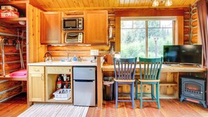 A cozy cabin-style kitchen with wooden cabinets, a refrigerator, a stove, and a television. - Montana Mountain Getaway - 1 Mi to Yellowstone! (Silver Gate)