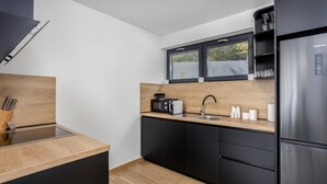 Et moderne køkken med et sort køleskab, en mikrobølgeovn, en brødrister og en vask.