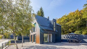 Et moderne hus med ståltag, store vinduer og en grusindkørsel.