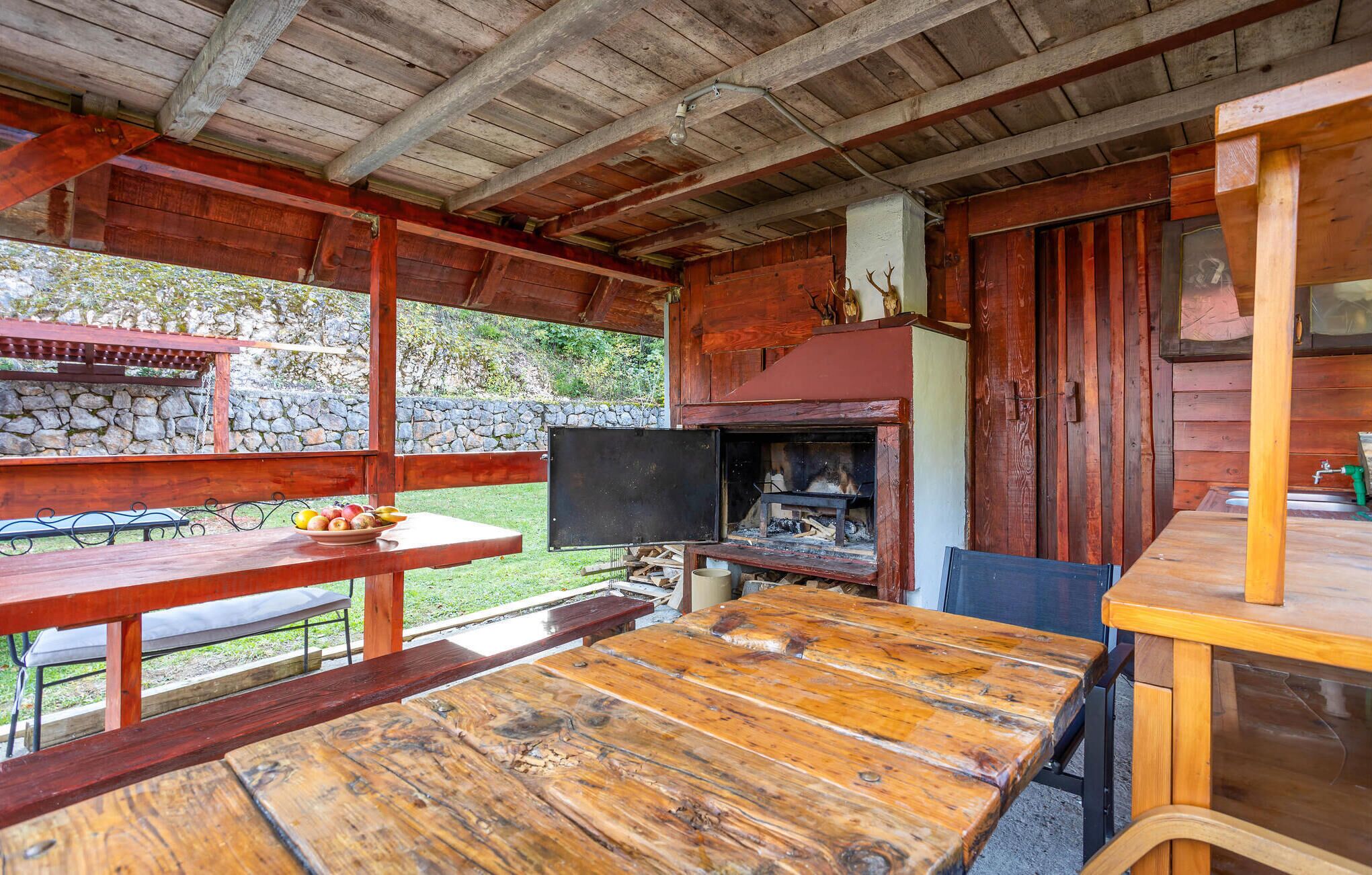 A rustic wooden cabin with a stone wall, a wooden table, and a fireplace.