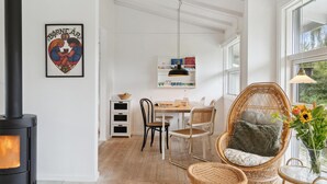 Ett mysigt rum med en öppen spis, möbler i rotting och en vacker utsikt genom stora fönster.