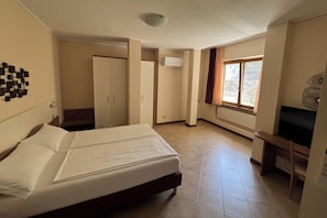 Une chambre d’hôtel avec un lit, un bureau, une armoire et une fenêtre.