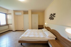 A bedroom with a bed, bedside tables, a wardrobe, and a radiator. - "Villa Imelda" spacious, bright apartments, garden or balcony, lake view (Limone Sul Garda)