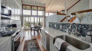 A modern kitchen with white cabinetry, a large island, and a view to the outdoors.