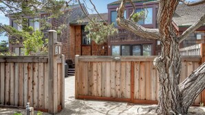 A wooden gate with a mailbox, a tree, and a building with a brown facade and windows.