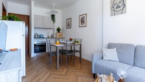 A modern kitchen with a dining area, a grey sofa, and a wall with framed artwork. - Cozy and bright 45 sqm apartment, perfect for 2 people, located on the first floor of a building with a lift (not suitable for disabled people). The accommodation is located in a neighborhood served by all the main services: bars, restaurants, supermarke (Pisa)
