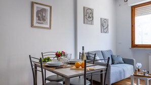 A dining area with a table set for four, a sofa, and artwork on the walls. - Cozy and bright 45 sqm apartment, perfect for 2 people, located on the first floor of a building with a lift (not suitable for disabled people). The accommodation is located in a neighborhood served by all the main services: bars, restaurants, supermarke (Pisa)