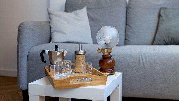 A coffee setup on a tray with a coffee pot, a grinder, and glasses on a white table in front of a grey sofa. - Cozy and bright 45 sqm apartment, perfect for 2 people, located on the first floor of a building with a lift (not suitable for disabled people). The accommodation is located in a neighborhood served by all the main services: bars, restaurants, supermarke (Pisa)