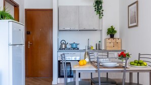 A compact kitchen with a refrigerator, stove, and dining area with chairs and a table. - Cozy and bright 45 sqm apartment, perfect for 2 people, located on the first floor of a building with a lift (not suitable for disabled people). The accommodation is located in a neighborhood served by all the main services: bars, restaurants, supermarke (Pisa)