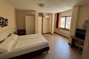 Una habitación de hotel con cama, escritorio, armario y ventana.