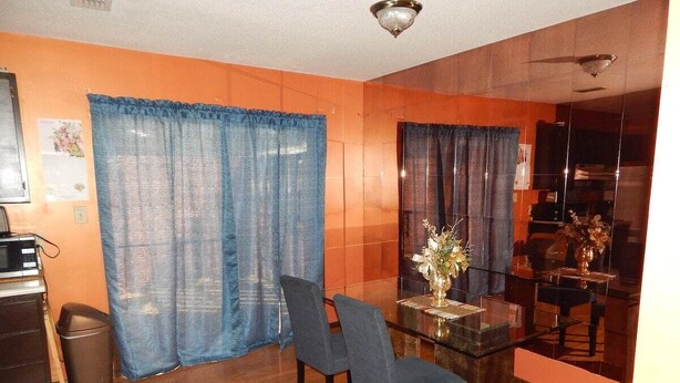 A dining area with a glass table, two chairs, and a vase with flowers. - Perfect Fayetteville Stay-cation in Cozy 2-Bed, 2-Bath Townhome (Fayetteville)