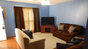 A living room with a beige sofa, a brown leather sofa, and a television. - Perfect Fayetteville Stay-cation in Cozy 2-Bed, 2-Bath Townhome (Fayetteville)