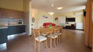 A modern kitchen with a microwave, a dining table with chairs, a red sofa, and a wall-mounted air conditioner. - "Villa Imelda" spacious, bright apartments, patio or balcony, lake view (Limone sul Garda)