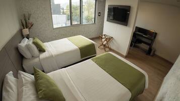Una habitación de hotel con dos camas, televisión, escritorio y ventana con vistas.