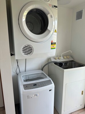 A laundry room with a front-loading washing machine, a dryer, and a sink.