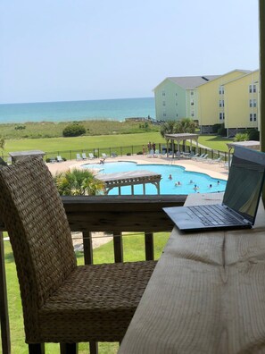 A view of a pool area with lounge chairs and a laptop on a table. - OceanScape- Beach and Sun in Surf City! (Surf City)