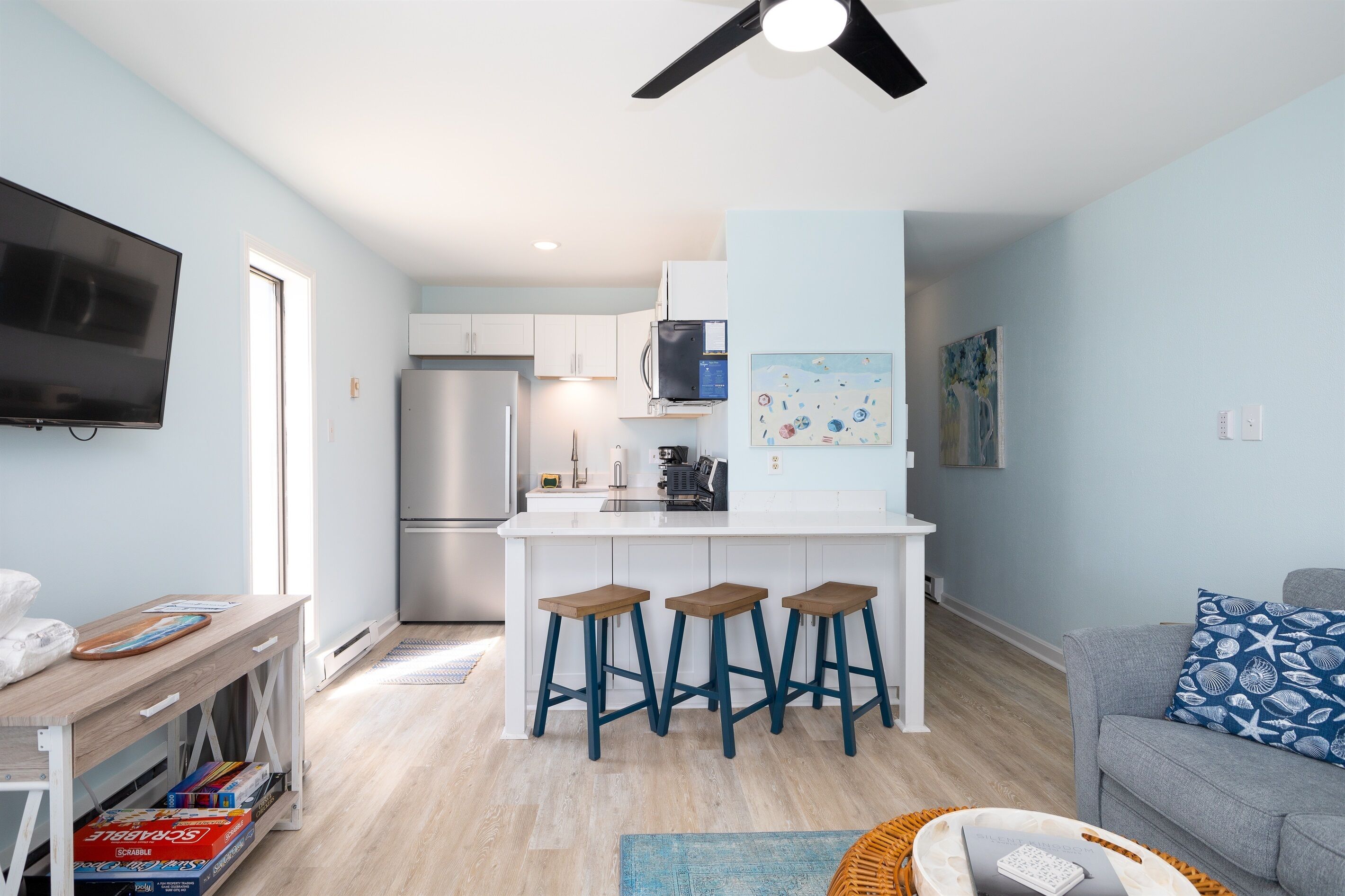A modern kitchen with a central island, bar stools, and a dining area.