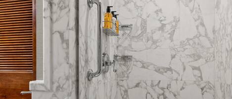 A shower with a marble wall and a wooden door.