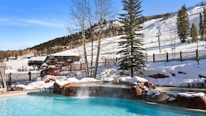 Ein Poolbereich mit Thermalquelle, umgeben von verschneiter Landschaft und Bäumen.