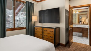 A hotel room with a bed, a TV, a dresser, a bathroom with a mirror, and a window with curtains. - The Ritz-Carlton Club 3BD Penthouse 4301, Ski-in & Ski-out (Aspen)