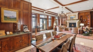 A spacious dining area with a wooden table and chairs, a fireplace, and a bookshelf.