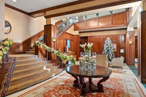 Step into the grand lobby, featuring a majestic staircase, elegant round table, and comfortable seating area.