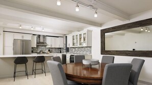 A modern kitchen with white cabinets, a stainless steel refrigerator, and a large island with bar stools. - Chateau Snow Unit 202 | Renovated Condo with Great Natural Light, Excellent Location (Aspen)