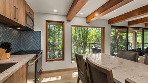 Une cuisine moderne avec des poutres en bois, de grandes fenêtres et un dosseret de carreaux disposés en motif chevron.