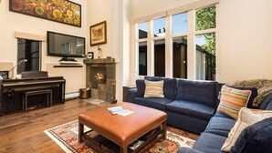 Ein Wohnzimmer mit Kamin, großem Fernseher, einer Couch und einem Couchtisch.