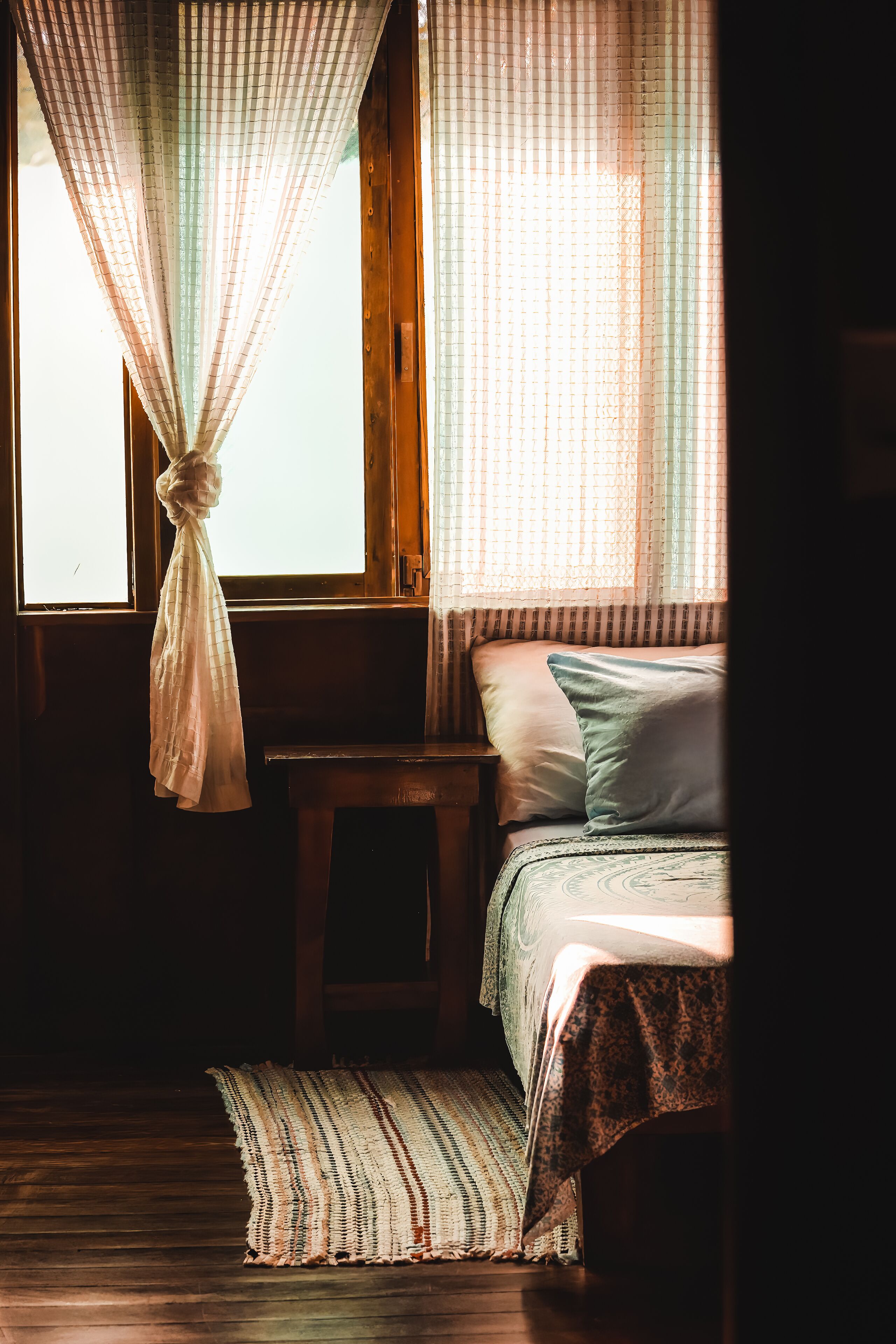A room with a bed, a small table, and a window with curtains.