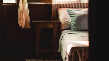 A room with a bed, a small table, and a window with curtains.