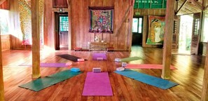 A yoga studio with wooden floors, colorful mats, and a central altar. - Ocean Forest Ecolodge Retreat (Drake Bay)