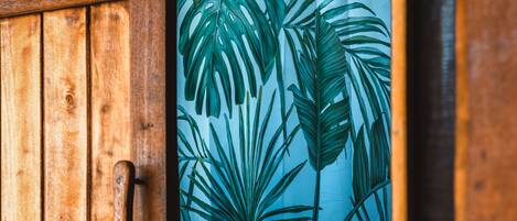 Una puerta de madera con cortina que presenta motivos de hojas tropicales.
