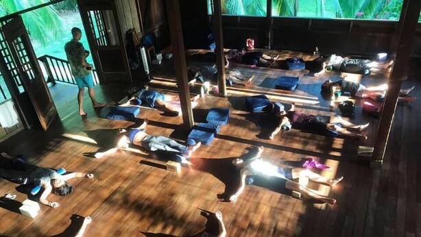 A yoga class in a room with wooden floors and large windows. - Ocean Forest Ecolodge Retreat (Drake Bay)