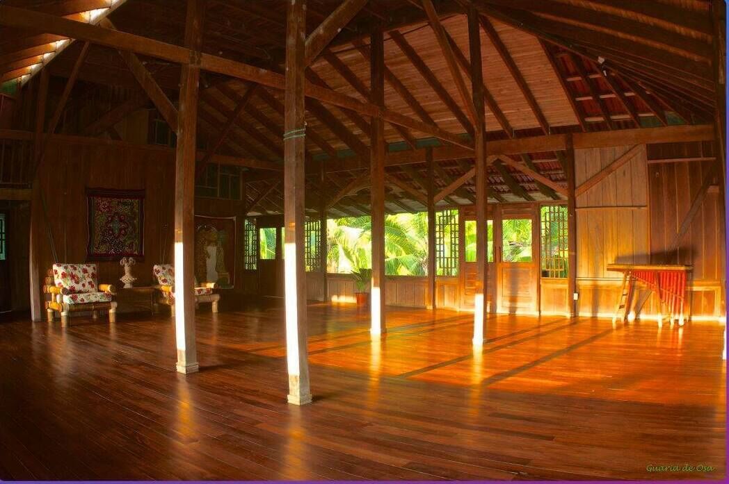 Un intérieur caractérisé par un plafond haut, des poutres en bois et un grand espace ouvert doté d’un plancher en bois.