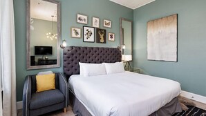 Ein Schlafzimmer mit einem großen Bett, einer kleinen Couch, einem Fernseher und Bildern an der Wand.