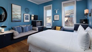 Un dormitorio con una cama grande, televisión, escritorio y ventana con vistas a la montaña.