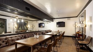 A restaurant with a long counter, leather booth seating, and a television mounted on the wall. - Independence Square 305 | Remodeled, 3rd Floor Hotel Room in Aspen's Best Location (Aspen)