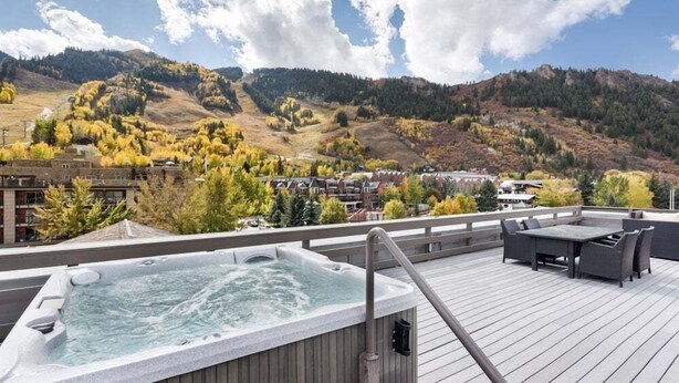 A rooftop deck with a hot tub, outdoor furniture, and a view of a mountainous landscape. - Independence Square 301 | Great Hotel Room with Excellent Location & Rooftop Hot Tub (Aspen)