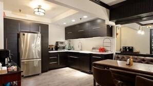 Una cocina moderna con armarios oscuros, electrodomésticos de acero inoxidable y un comedor con mesa de madera y sillas de cuero.