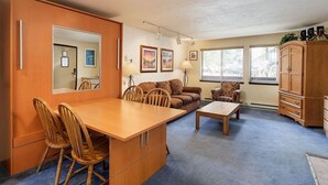 A compact living space with a dining area, a sofa, a coffee table, and a cabinet.