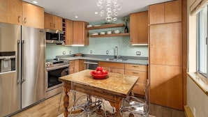 Una cocina moderna con electrodomésticos de acero inoxidable, armarios de madera y una isla central con un bol rojo.