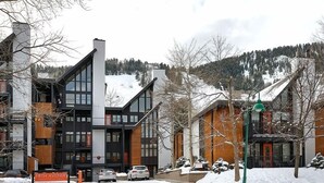 Ein modernes Gebäude mit großen Fenstern und einer Fassade aus Schwarz und Holz.