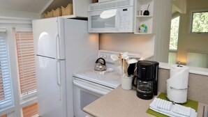 A compact kitchen with a refrigerator, microwave, stove, and coffee maker. - Old Hundred Unit 102 | Townhouse with Treetop Views & Excellent Location, 3 Blocks to Ski Slopes (Aspen)
