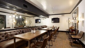 A restaurant with a long wooden table and leather booth seating, a large mirror, and wall-mounted televisions. - Independence Square 213 | Spacious Hotel Room with 2 Queen Beds, Wet Bar, and Sitting Area (Aspen)