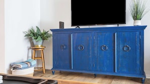 A blue cabinet with a flat-screen TV on top, a small stool with a plant, and a woven basket with a blanket. - Rustic Retreat Your Own Private Retreat in the Heart of Branson! (Branson)