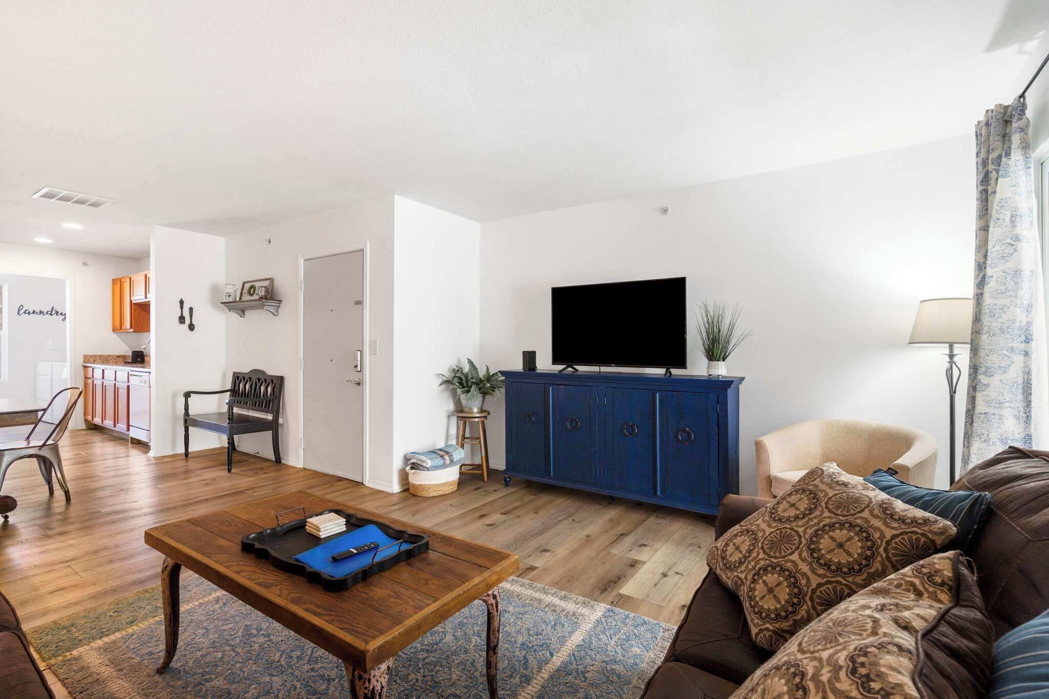 Una sala de estar con una mesa baja de madera, un sofá marrón, un mueble azul y un televisor.