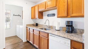 A kitchen with wooden cabinets, a granite countertop, a sink, a toaster, a coffee maker, and a dishwasher. - Rustic Retreat Your Own Private Retreat in the Heart of Branson! (Branson)