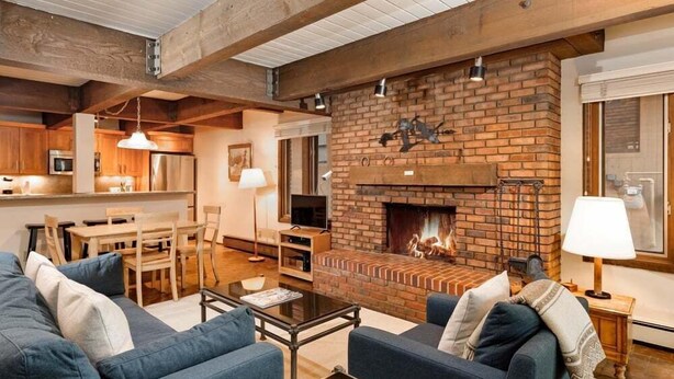 Amplia sala de estar con chimenea, vigas de madera y comedor.
